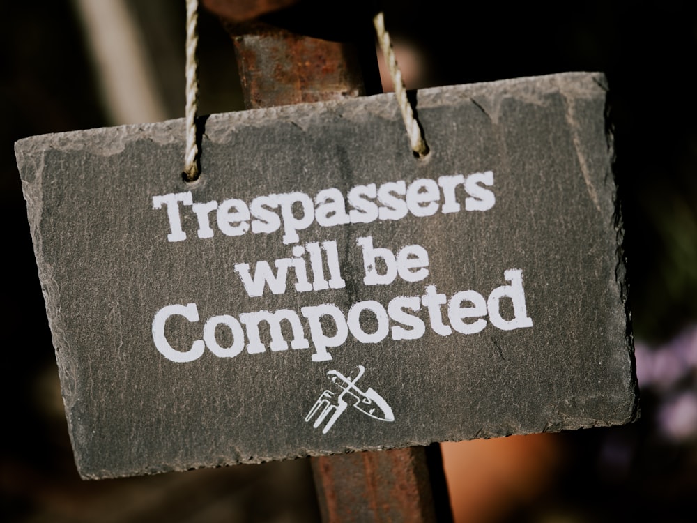 gray and white trespassers will be composted sign