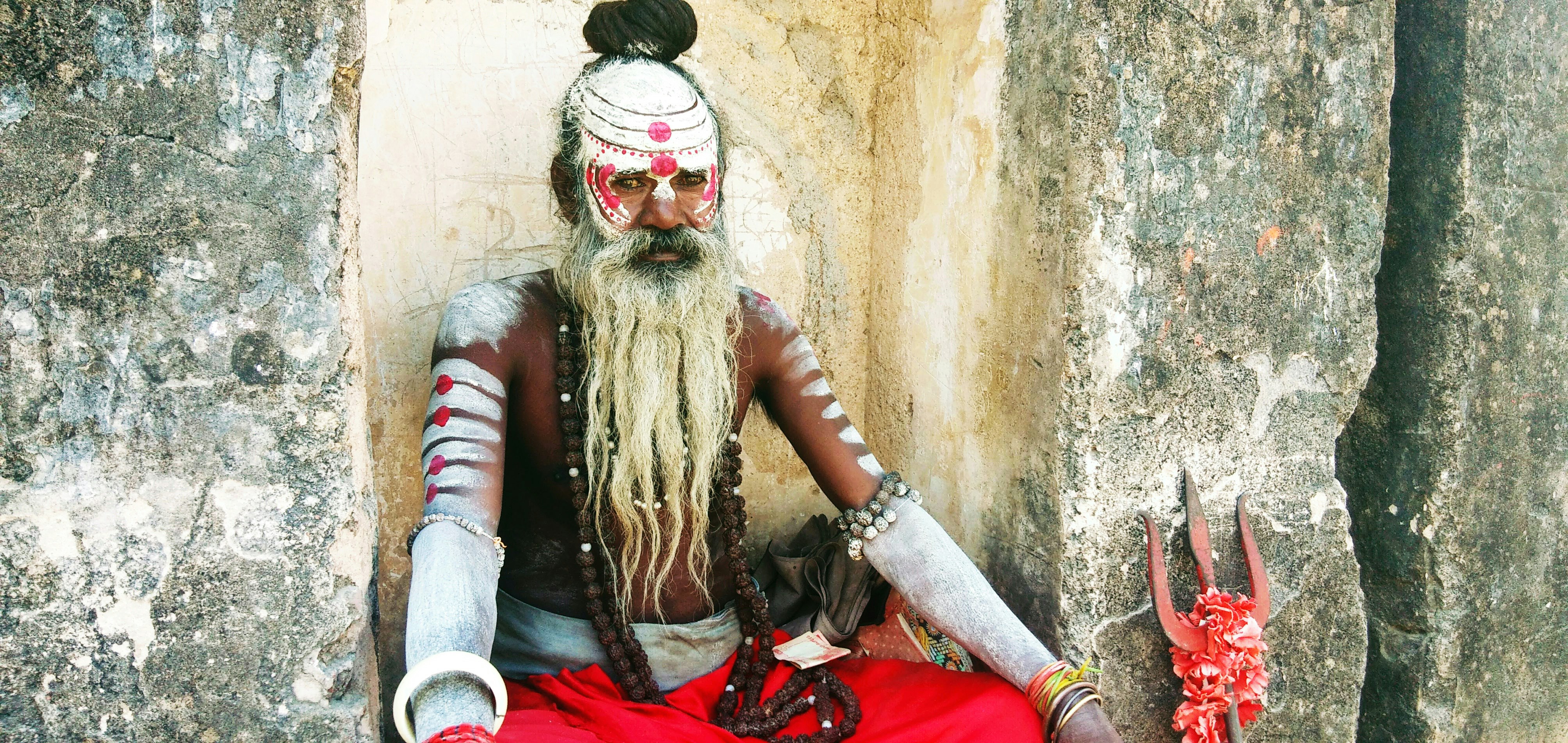man with body paint sitting near beige wall