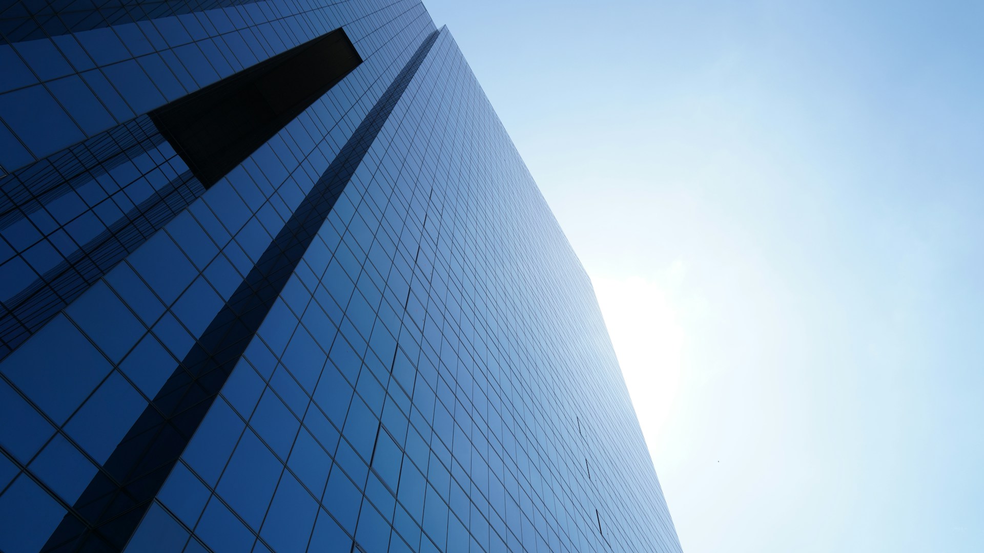 tall blue glass paneled building under clear blue sky