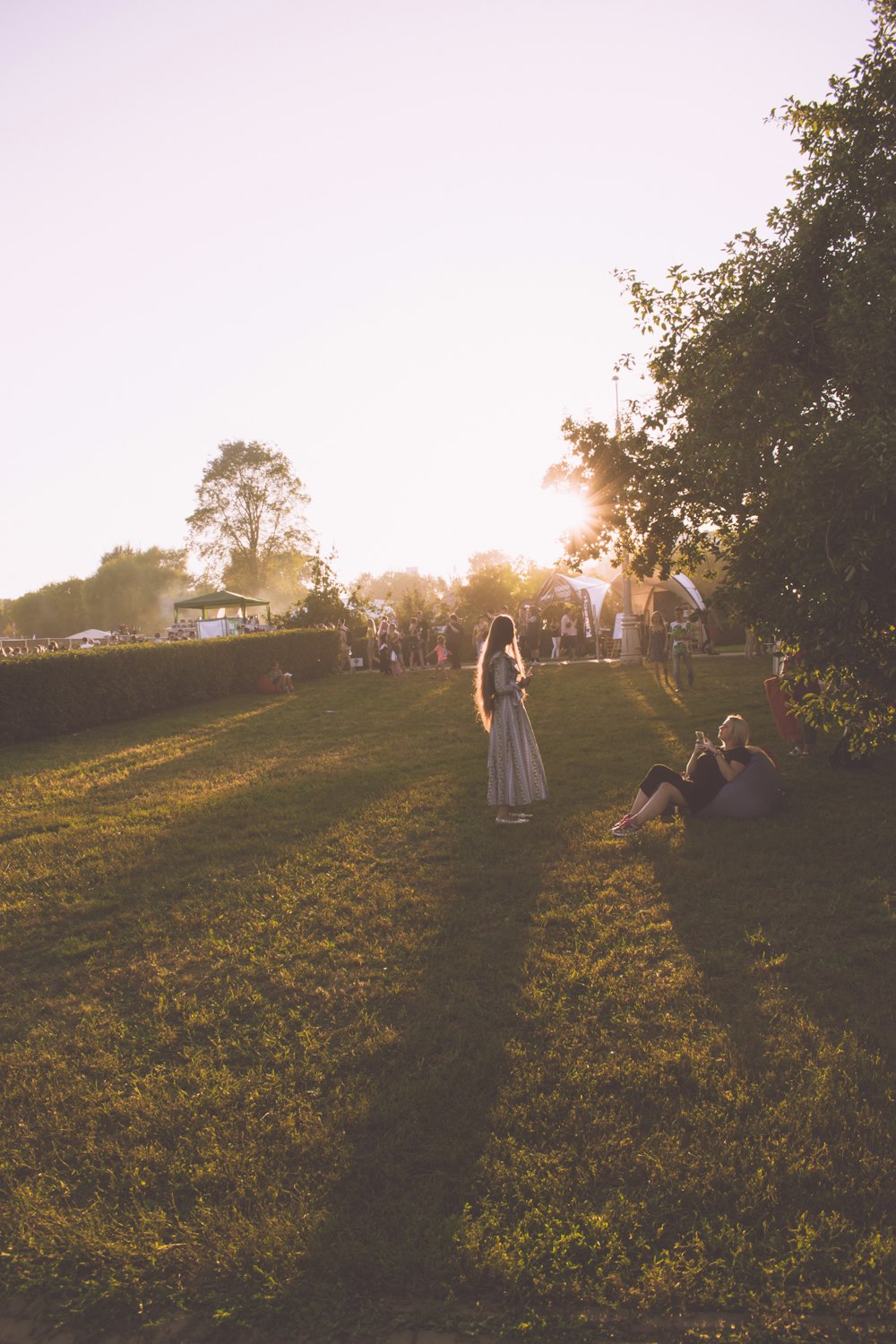 woman standing in front woman sitting on beanbag chair beside tree