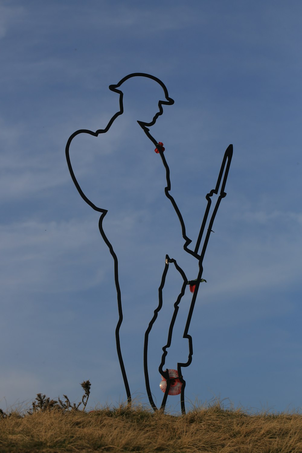 uma escultura de um homem segurando um pau no topo de uma colina