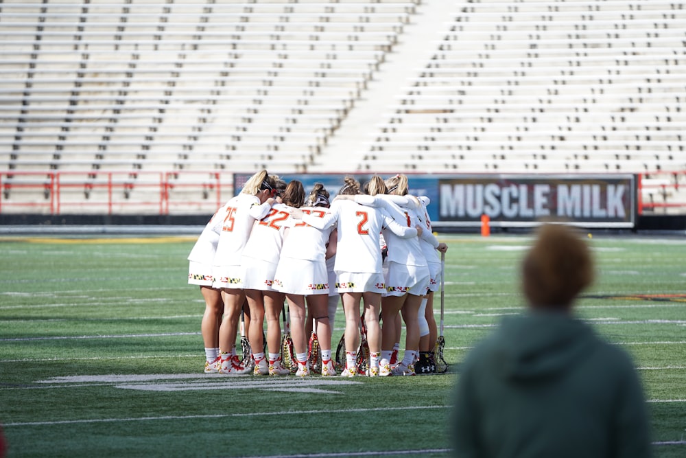 all women lacrosse team on huddle at the field