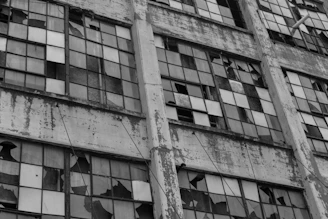 A haunting black and white photograph capturing the cracked facade of an abandoned urban building.
