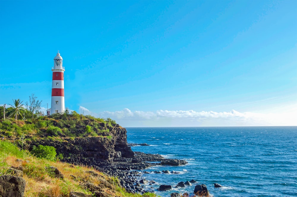 white and red lighthouse on grass field