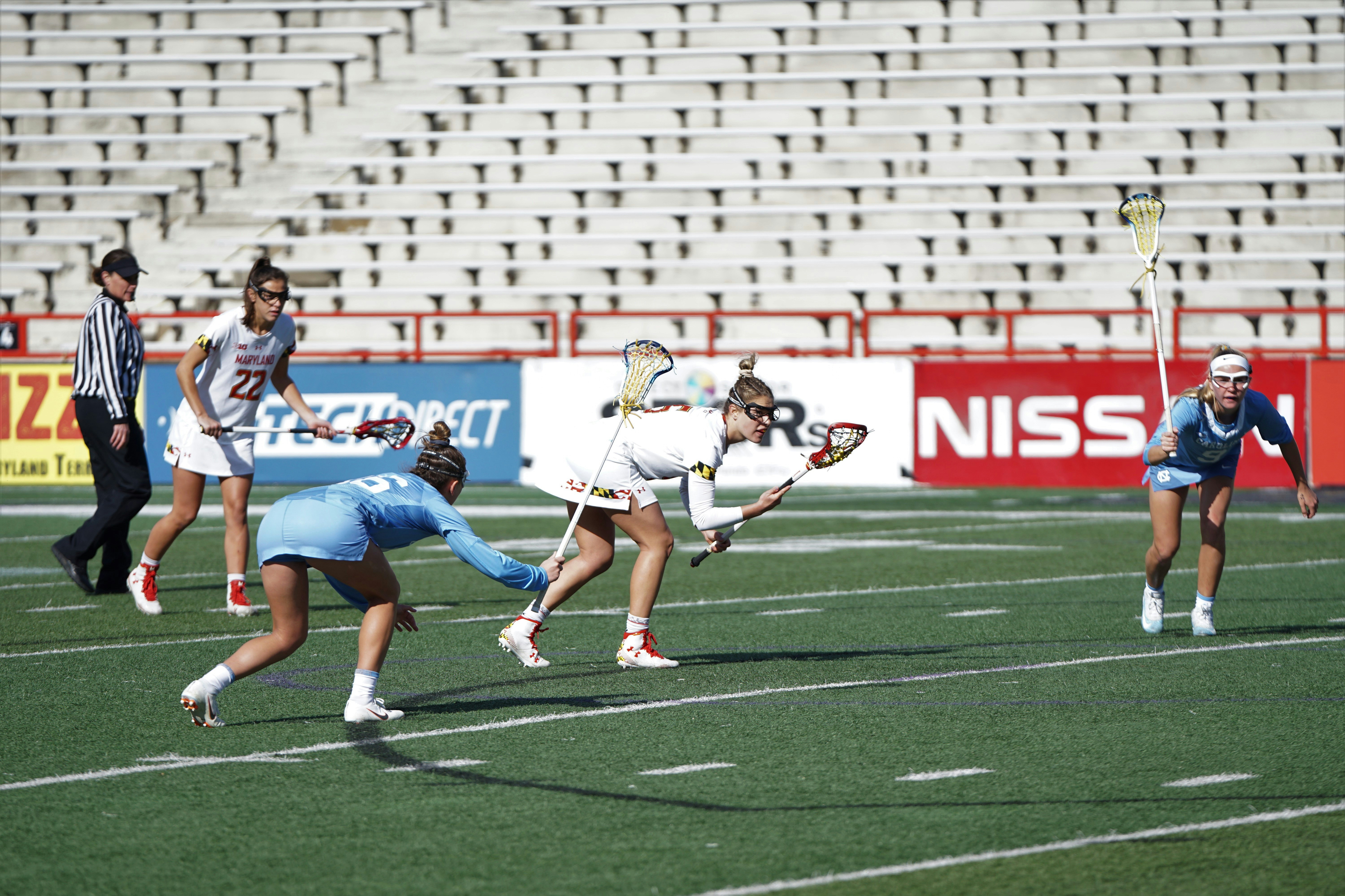 sekelompok wanita bermain lacrosse di lapangan