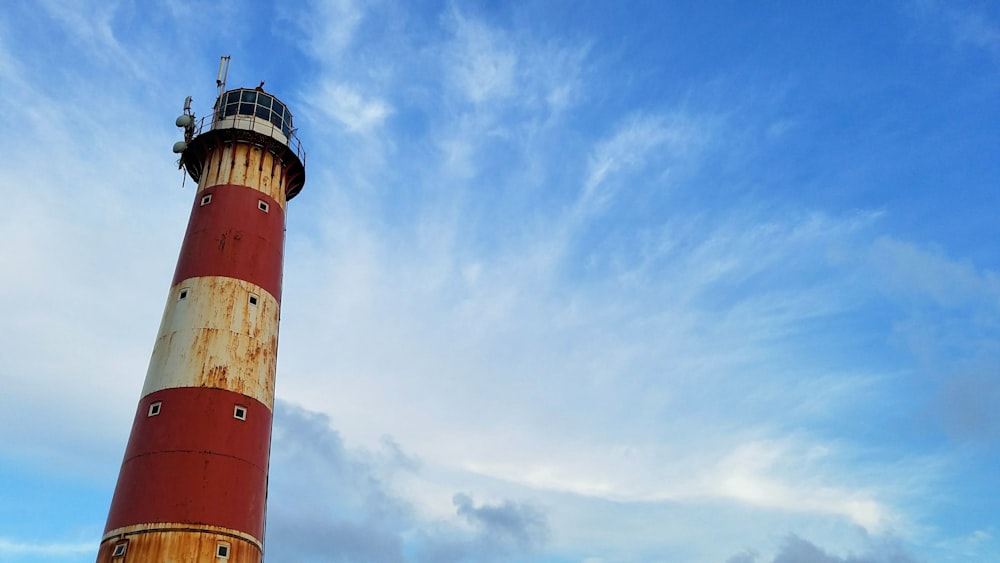 Faro rojo y blanco bajo un cielo azul claro