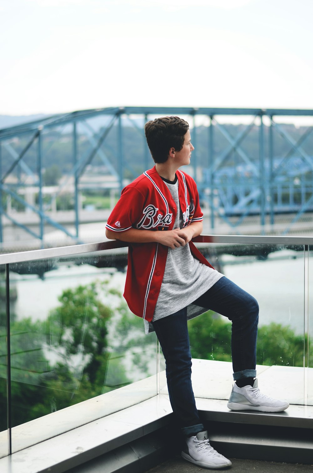 boy leaning on gray stainless steel railings during daytime