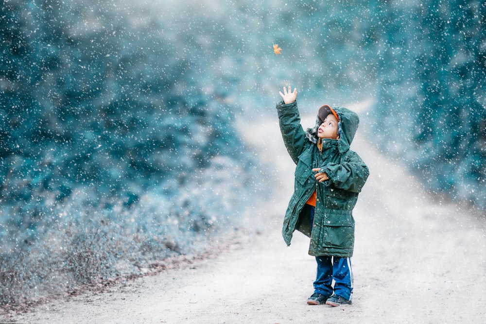 selective focus photography of standing boy reaching for butterlfy