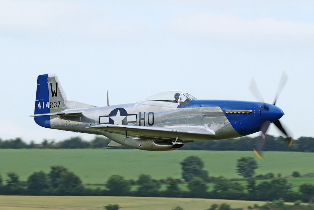 white and blue plane above green field