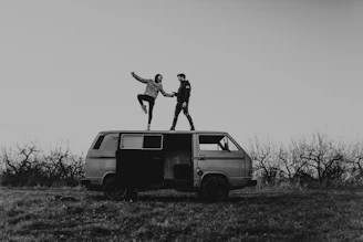 grayscale photography of man and woman standing on van