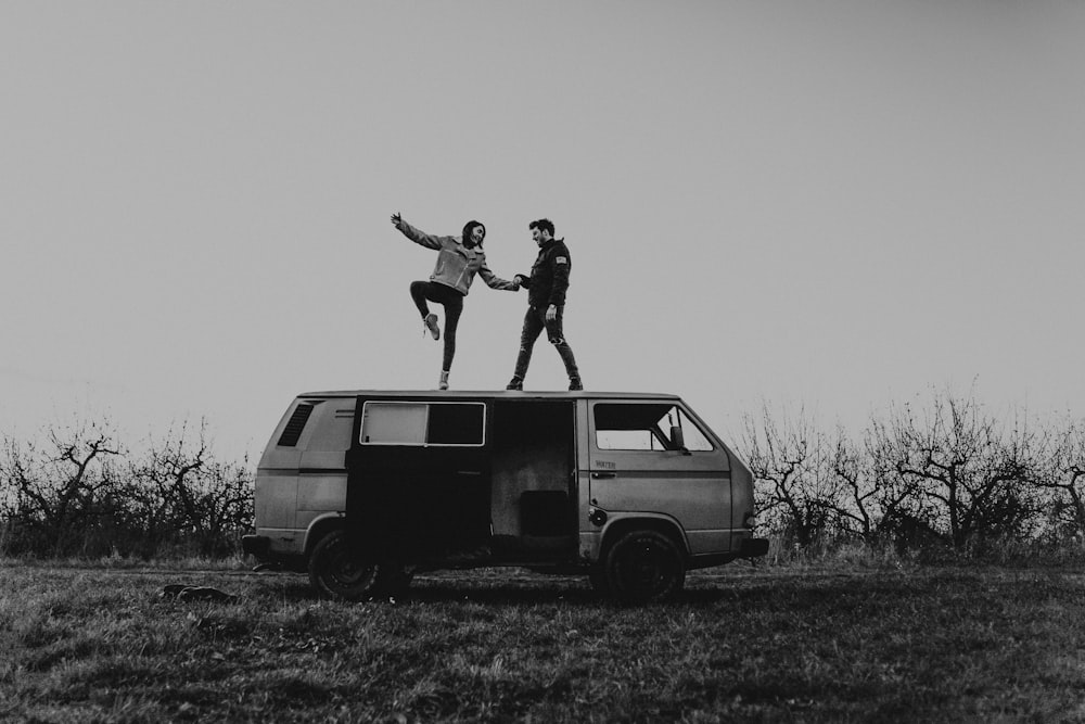 grayscale photography of man and woman standing on van