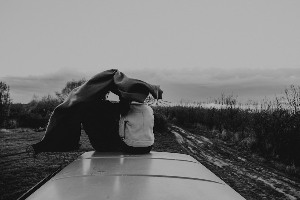 two person sitting on top of vehicle grayscale photography