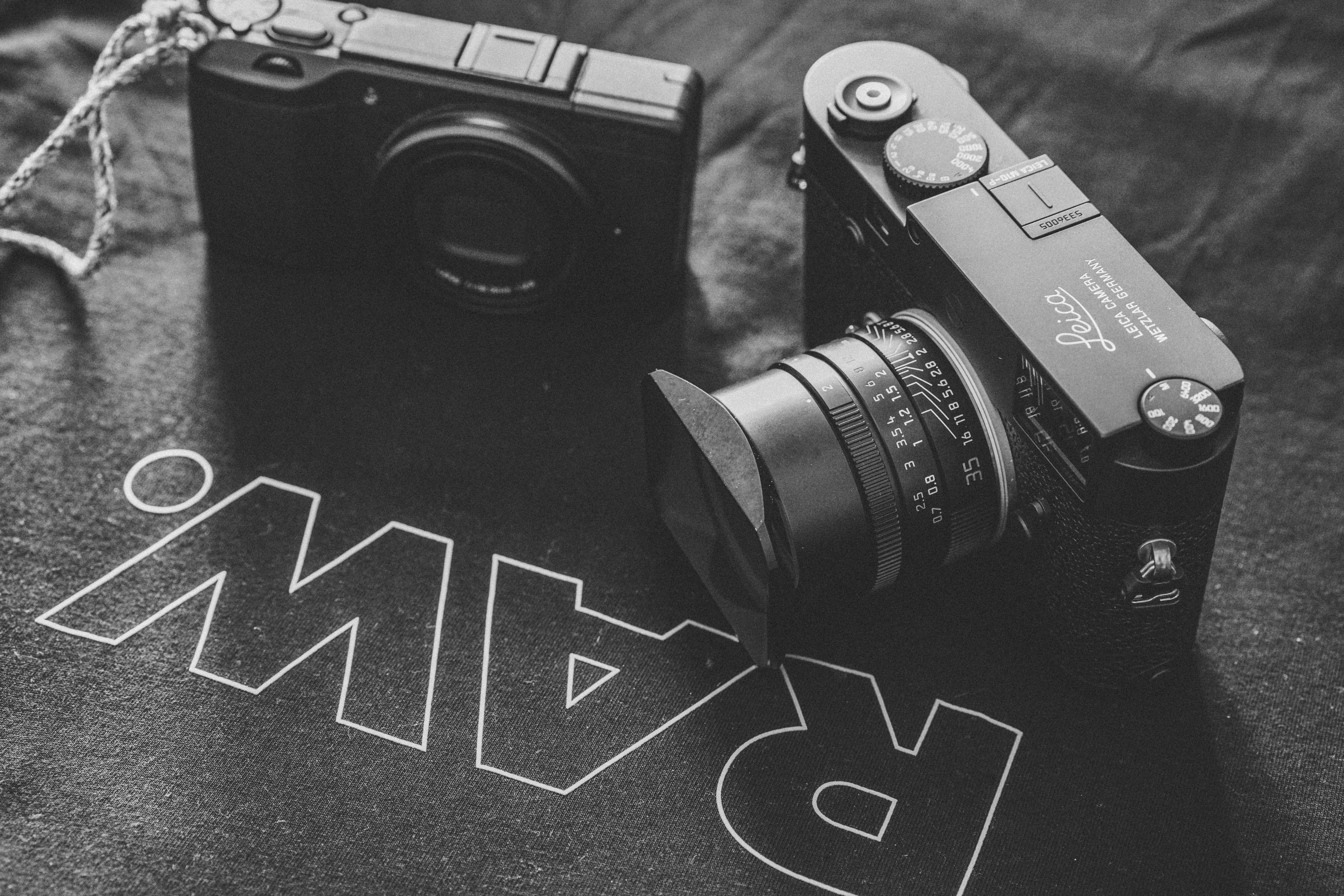 Grayscale photography of two pointandshoot cameras on black Raw