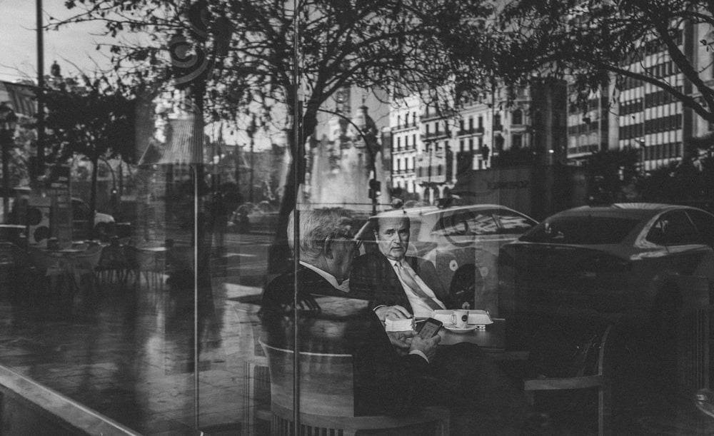 grayscale photography of two men inside building with glass wall