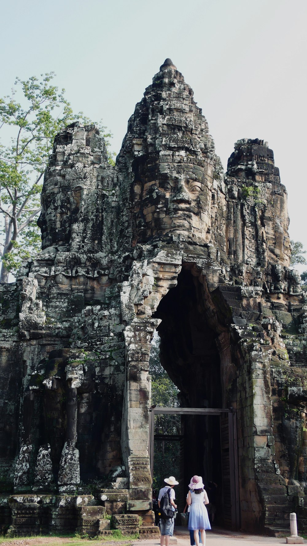 two person standing under gray rock formation