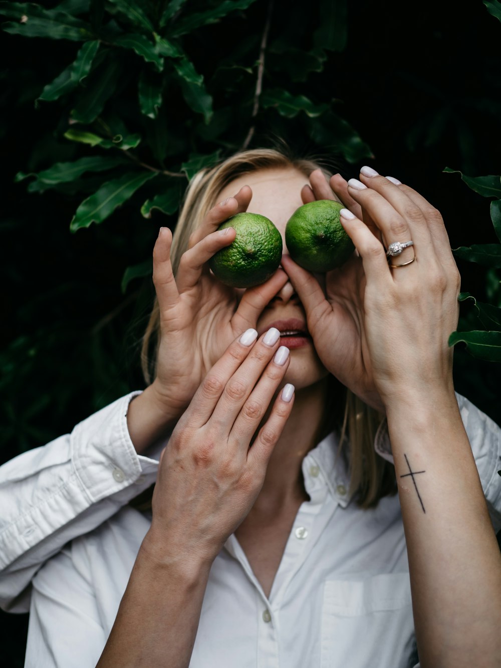 mulher cobrindo os olhos usando frutas verdes