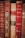 A collection of vintage books with ornate spines in various shades of red and brown. The titles and authors, such as A. France and Lamartine, are embossed in gold lettering, adding a sense of history and classic elegance to the scene.