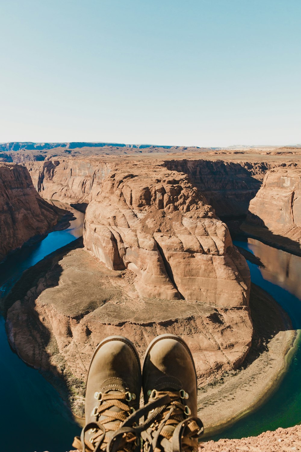 person wearing brown leather boots at Horseshoe bend, Arizona during daytime