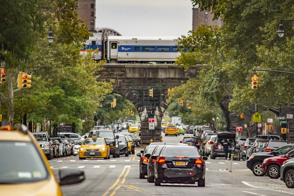 vehicle passing on road between green trees during daytime