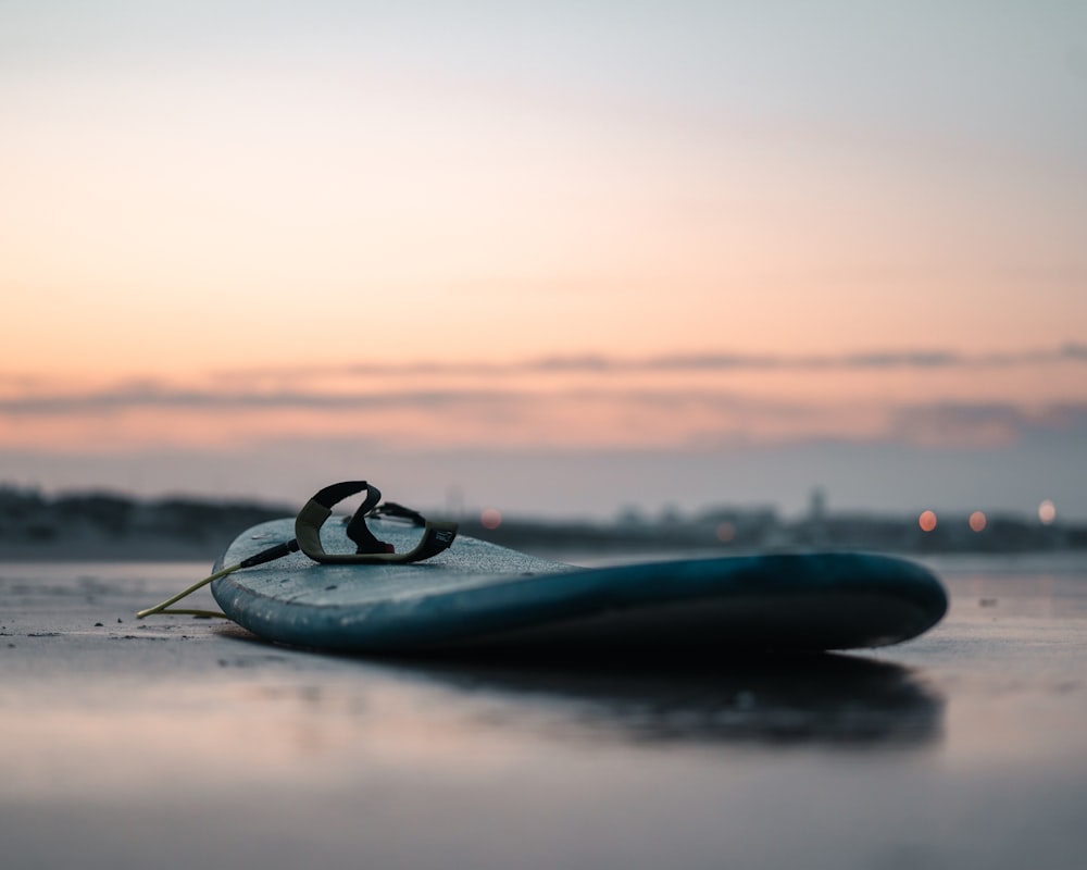 a surfboard laying on the beach at sunset