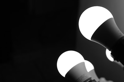 Three illuminated LED light bulbs against a dark background, with a focus on the brightness and contrast between the light bulbs and their surroundings.