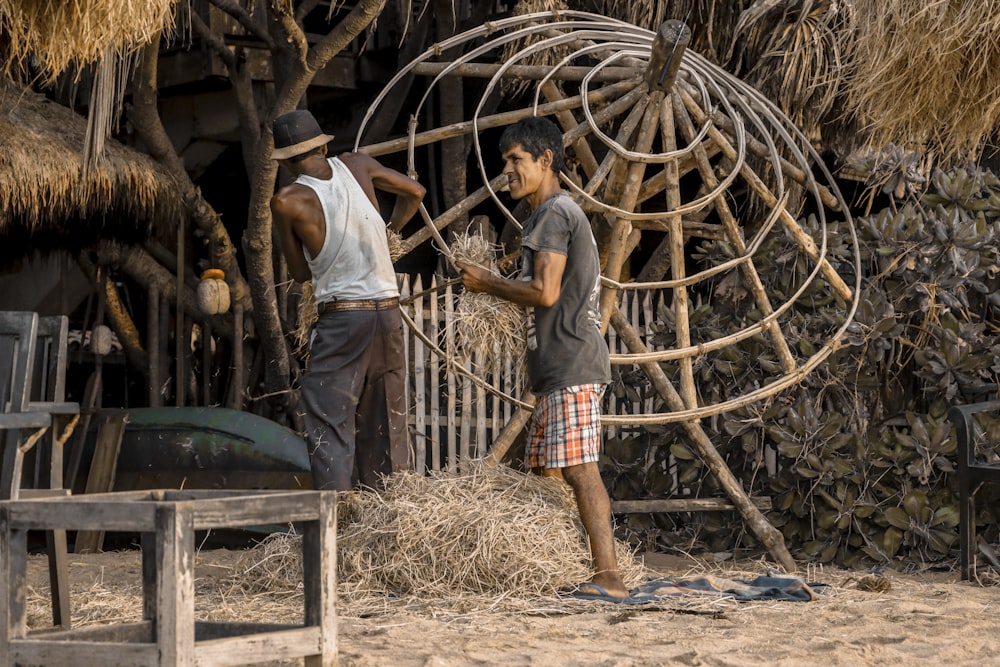 man wearing white tank top beside man holding hay outdoor