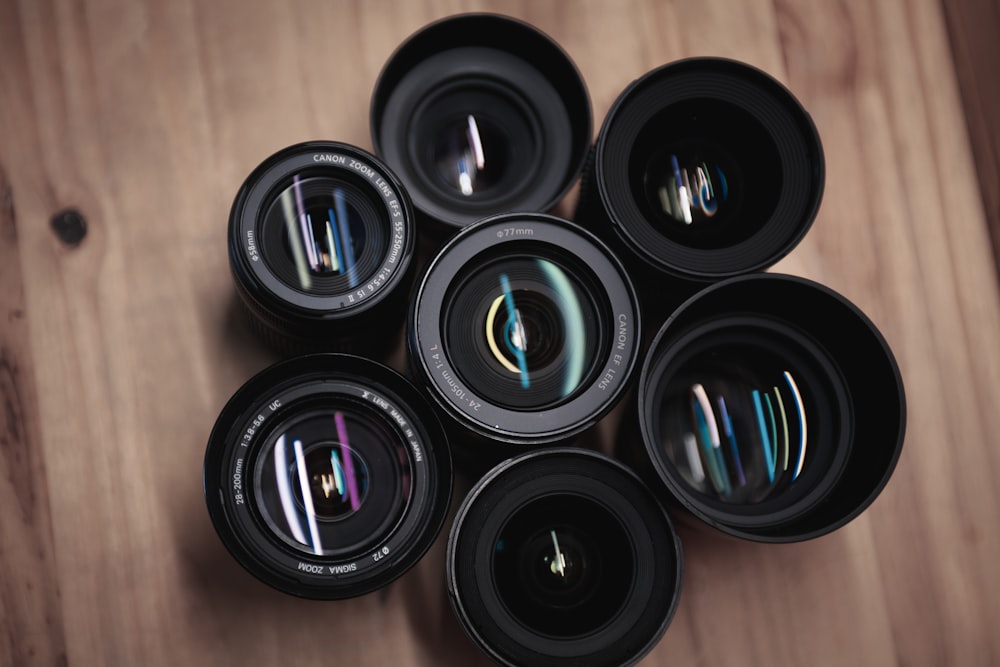 seven black camera zoom lenses on table