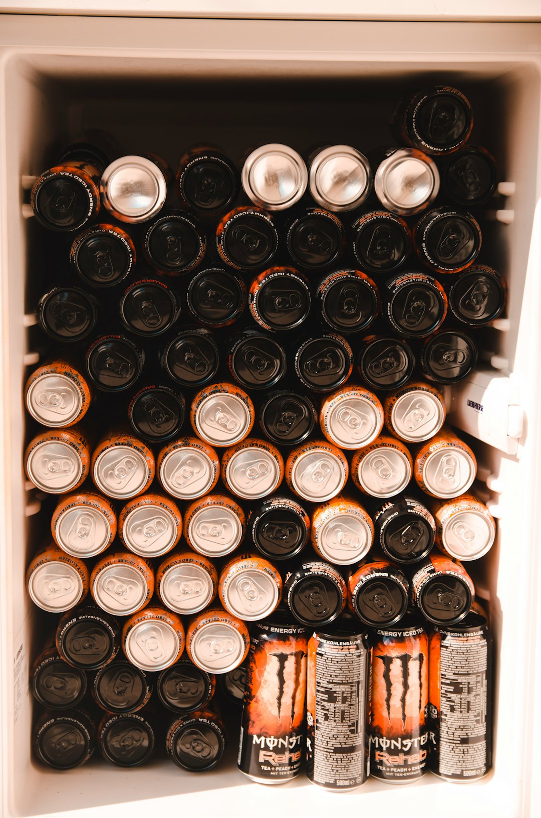 black and brown energy drink cans in white refrigerator