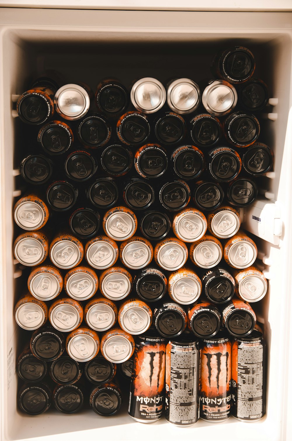 black and brown energy drink cans in white refrigerator