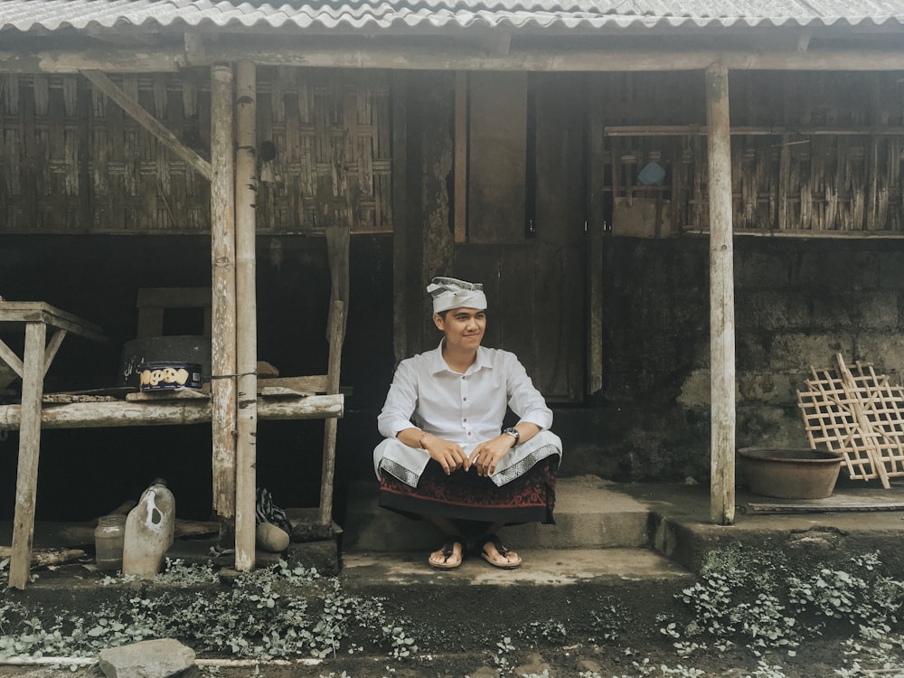 man sitting on concrete stairs near house