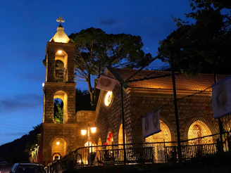 A nighttime shot of a church illuminated softly, with digital bell sounds resonating through the neighborhood.