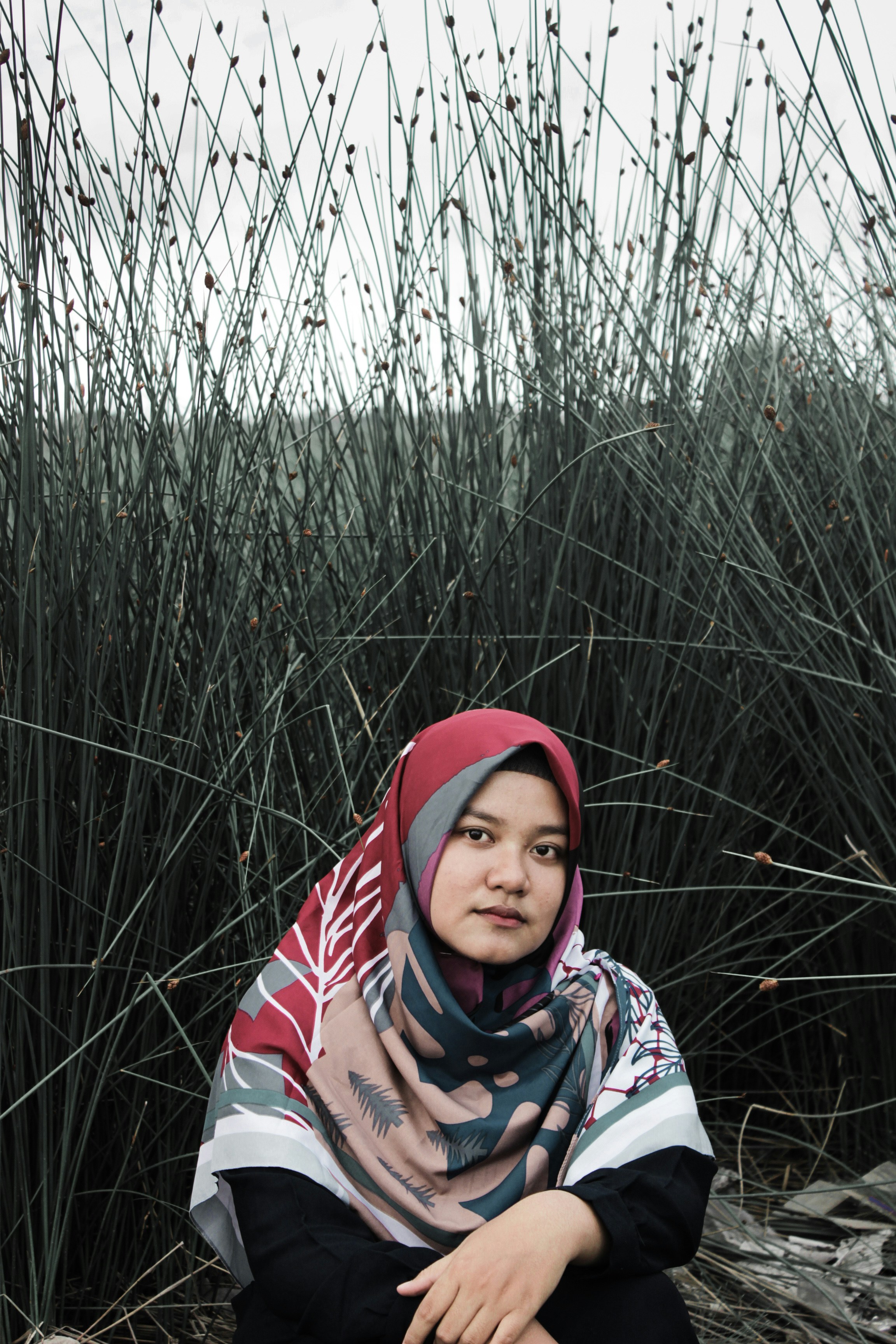 wanita duduk di samping rumput hijau