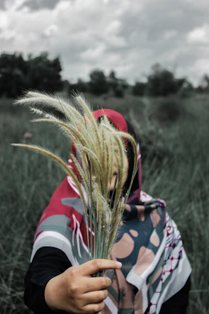 Close-up of a hand holding a bouquet of multicolored scarves against a sunny backdrop.