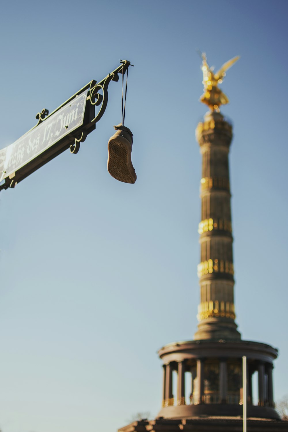 selective focus photography of shoe hanging on street light