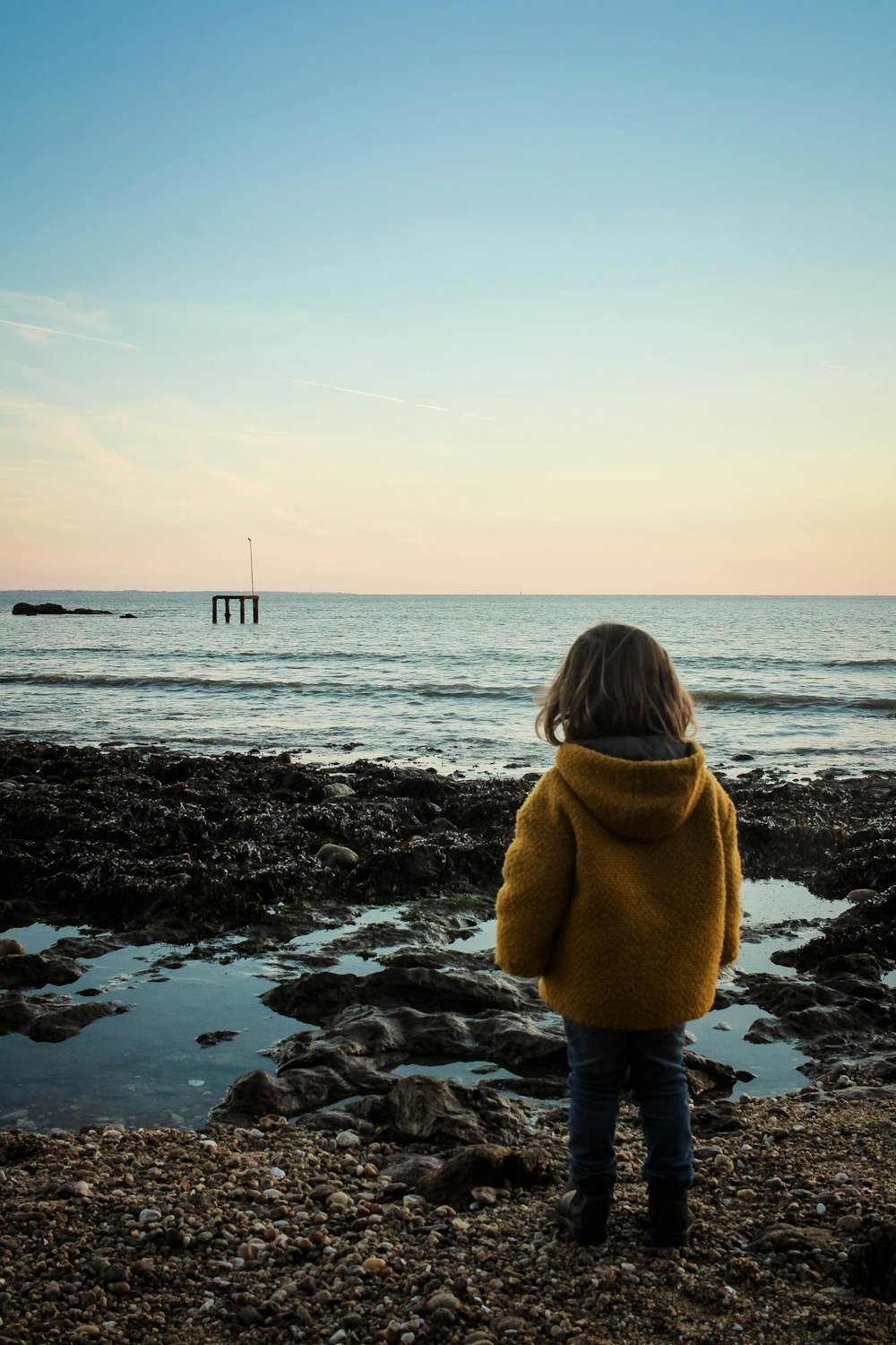 toddler standing beside body of water