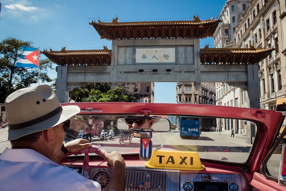 man driving red Taxi during daytime