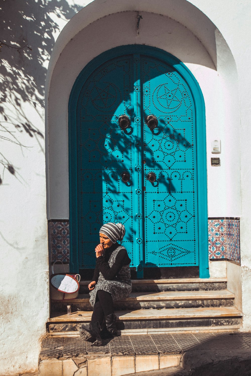 青い木製のドアのそばに座っている女性