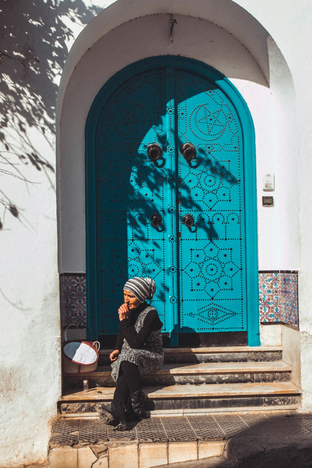 Mujer sentada al lado de la puerta de madera azul