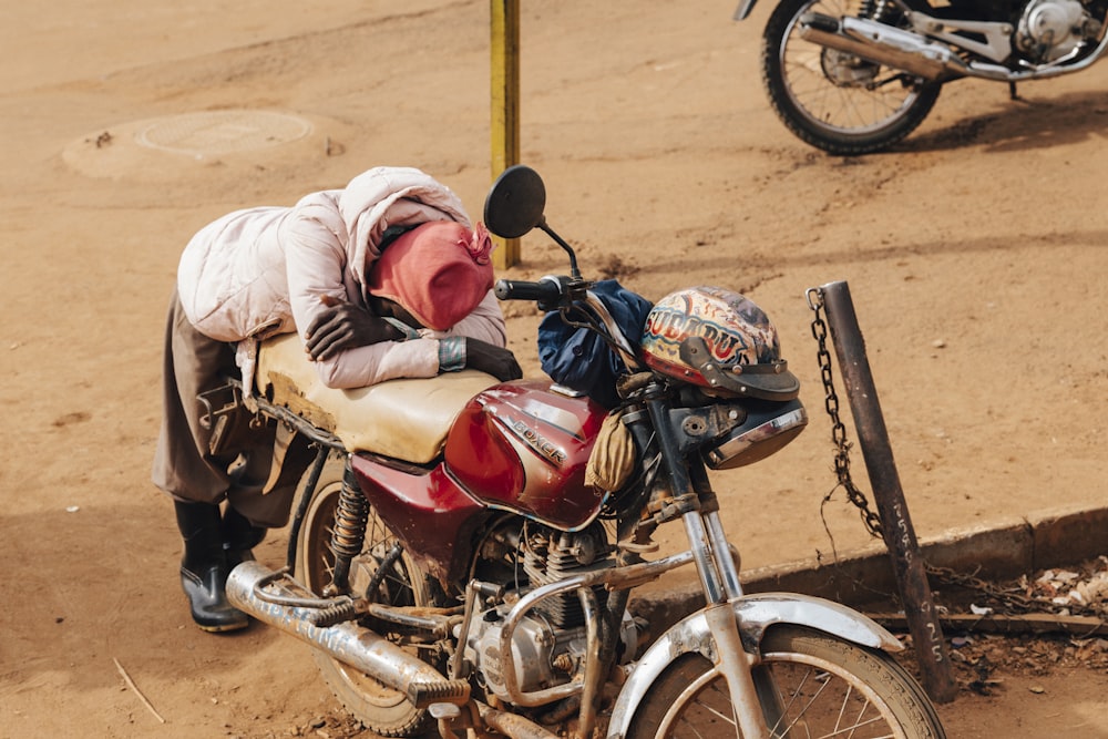 homme debout à côté d’une moto standard rouge