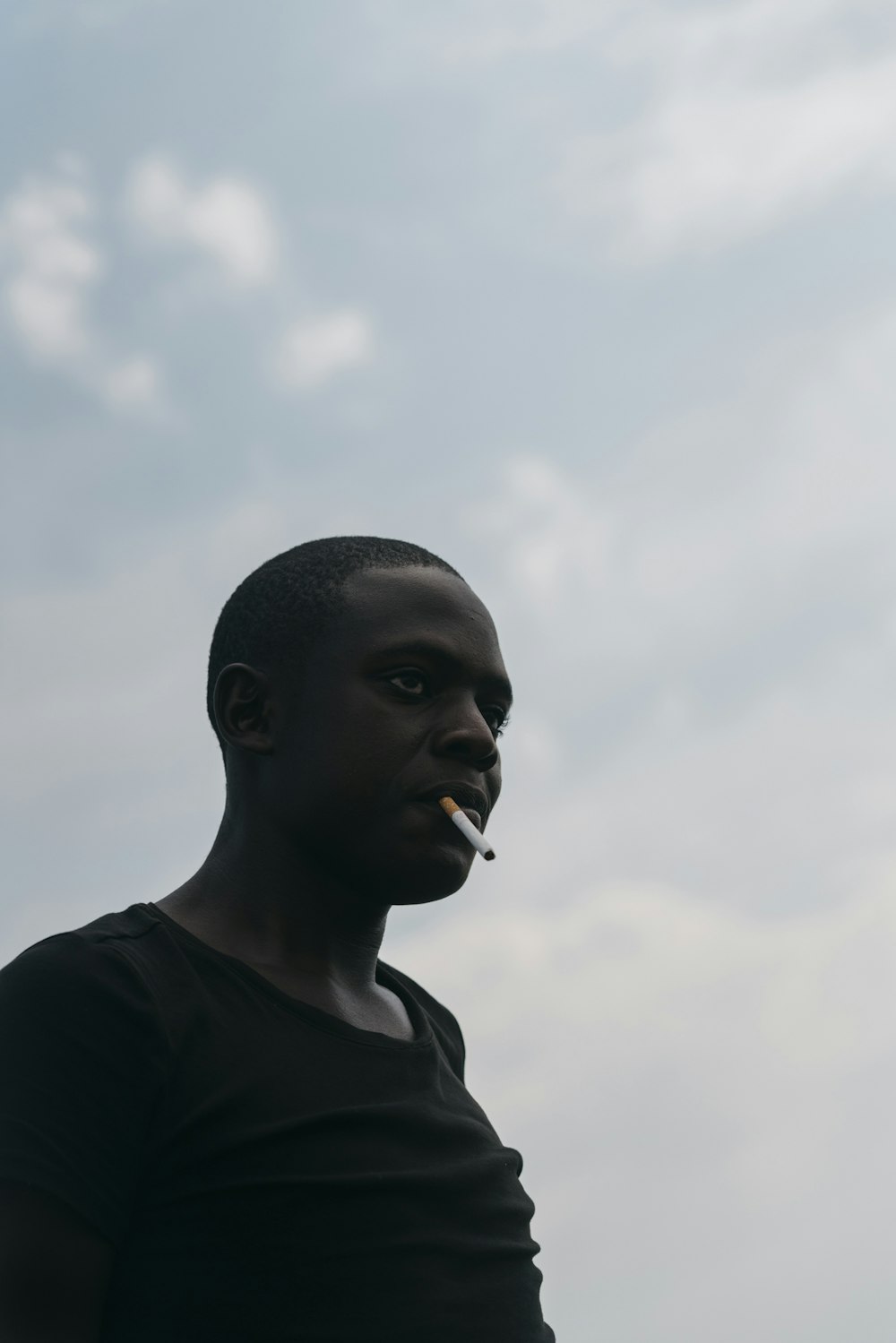 hombre fumando bajo nubes blancas