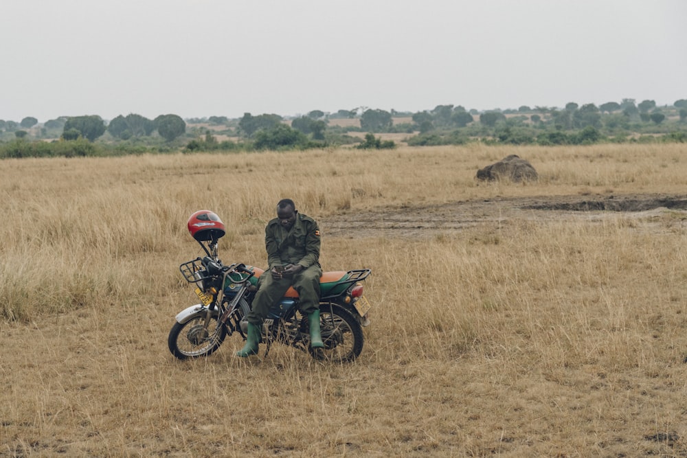 man sitting on green motorcycle in the middle of grass