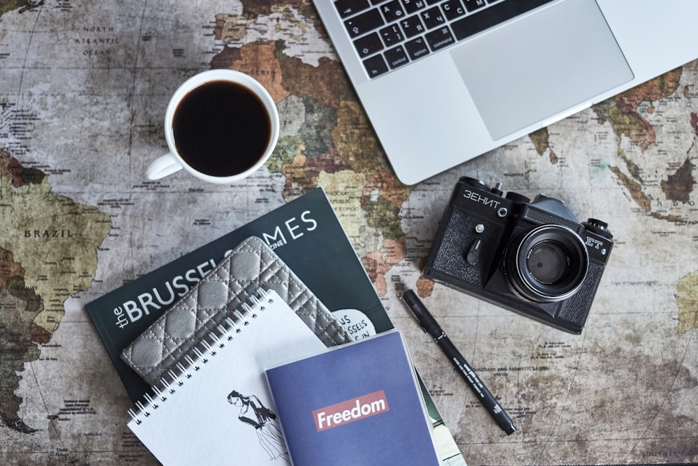 black camera beside laptop and mug