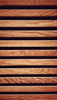 Vertical wooden slats of mixed hardwoods forming a contemporary cladding design.