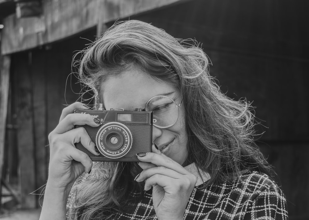 grayscale photo of woman holding DSLR camera