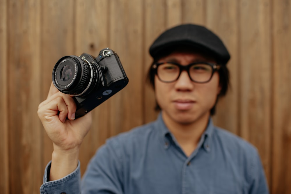 man standing while holding black camera