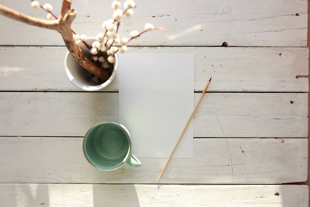 green ceramic cup on white paper