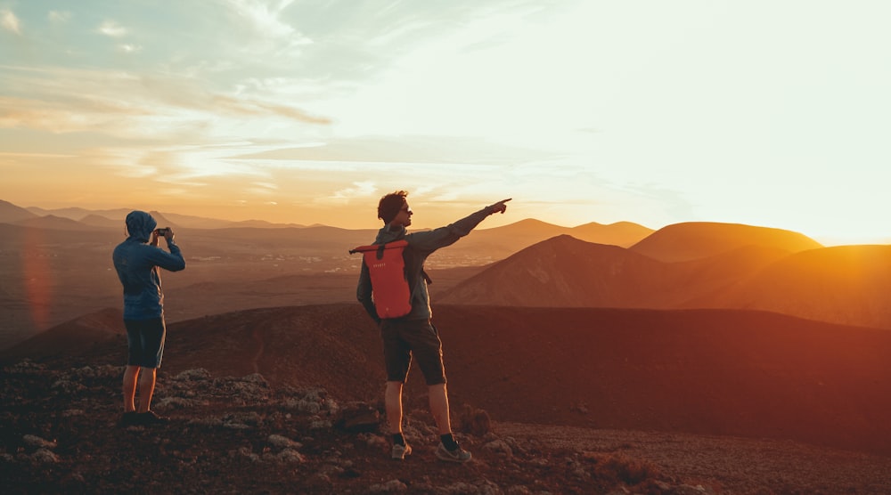 Dos personas de pie en la montaña durante la puesta del sol