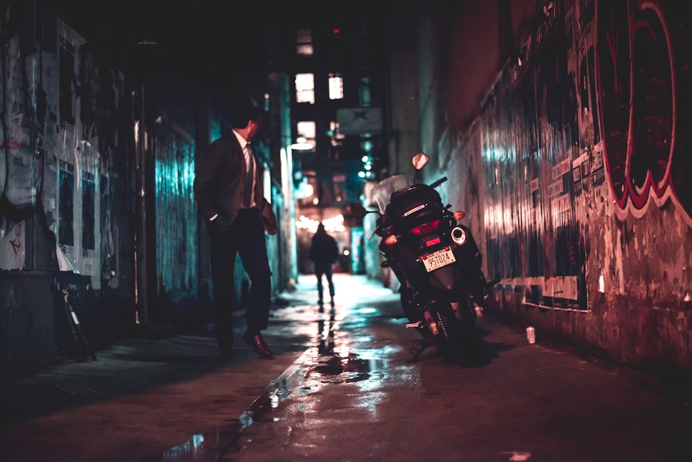 man walking beside black motorcycle