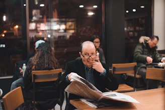 A diverse group of people discussing news articles in a cafe.