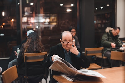 A diverse group of people discussing news articles in a cafe.